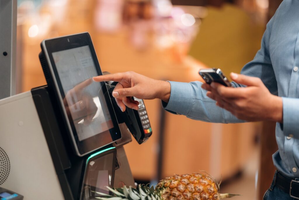 スーパーマーケットにて、クレジットカードで支払いをする男性客